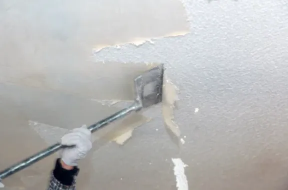 Popcorn ceiling texture being scraped off a ceiling
