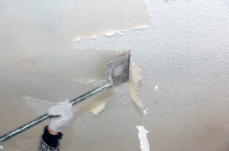 Popcorn ceiling texture being scraped off a ceiling