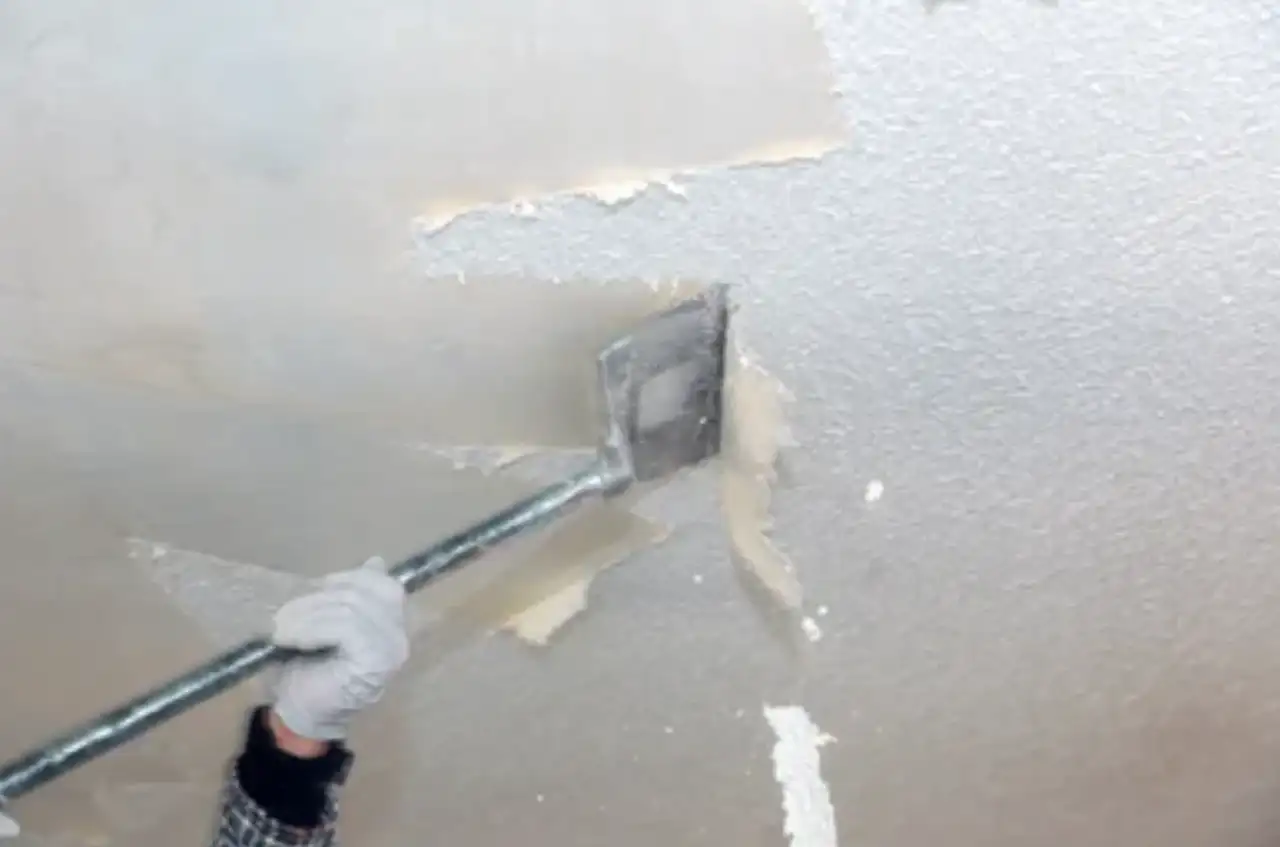 Popcorn ceiling texture being scraped off a ceiling